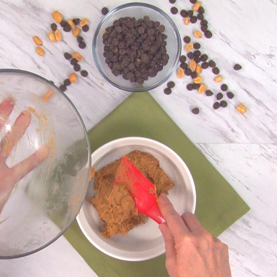 Transerring the peanut butter mixture to the bottom of a white dish