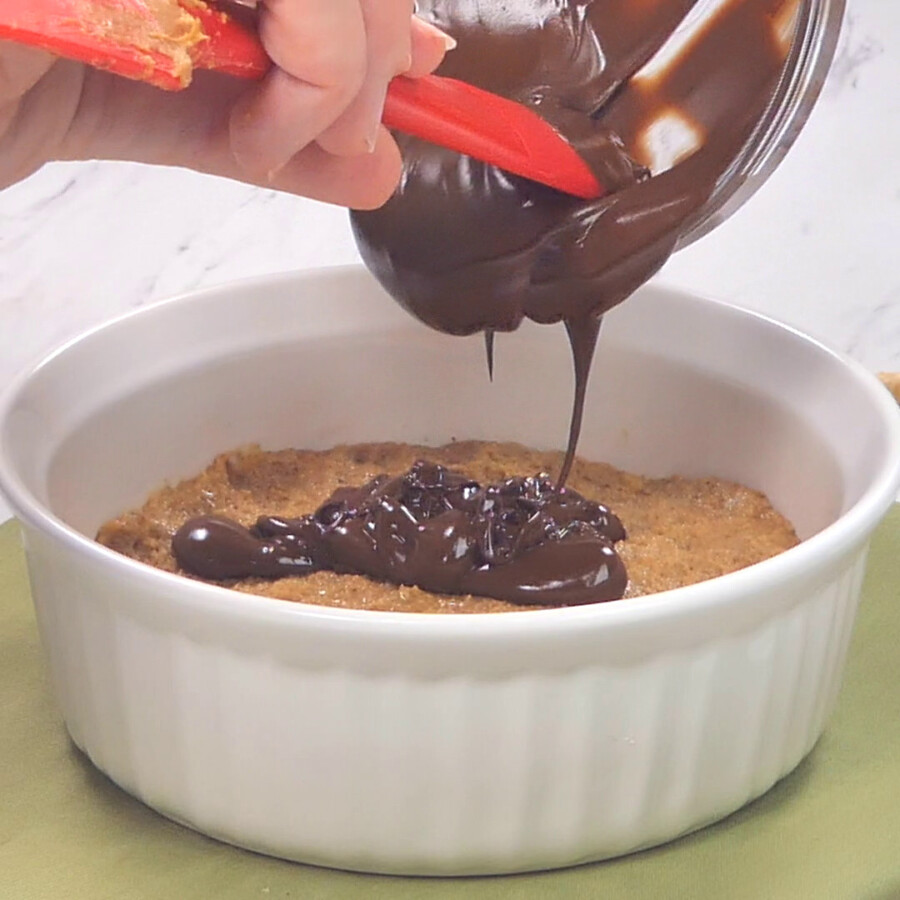 Pouring melted chocolate over the top of the peanut butter base