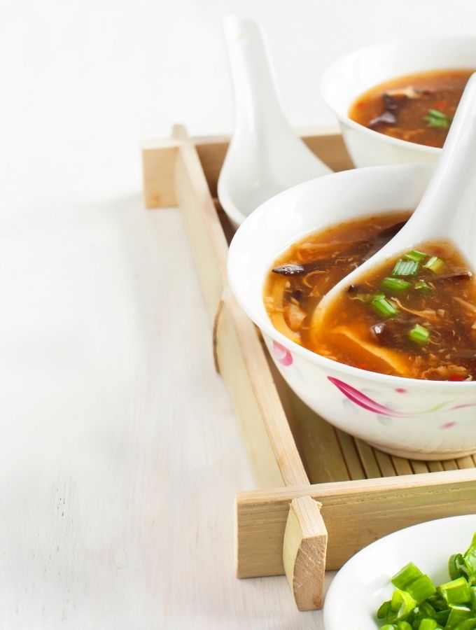 Keto Egg Drop Soup served in a white ceramic bowl on a bamboo platter