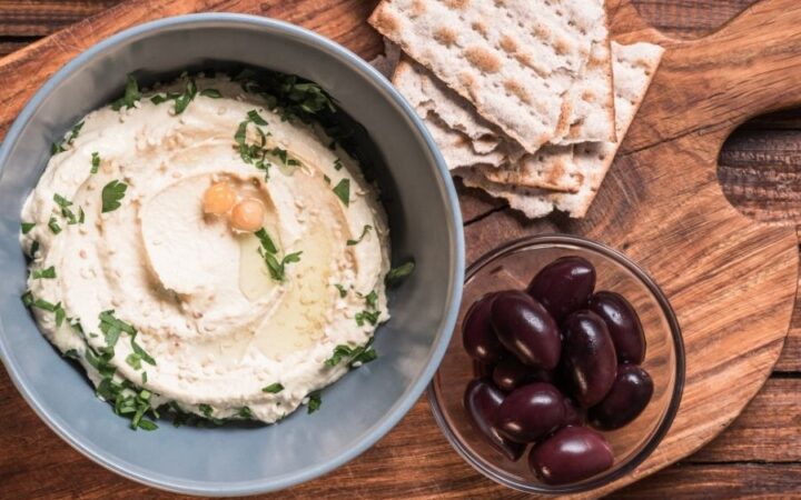 Hummus in a bowl on top of a wooden cutting board