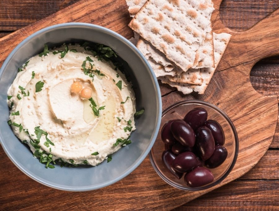 Hummus in a bowl on top of a wooden cutting board