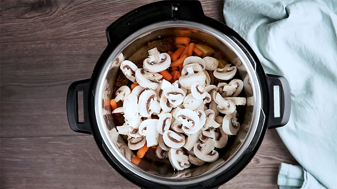 Overhead shot of the mushrooms and carrots added to the Instant Pot.