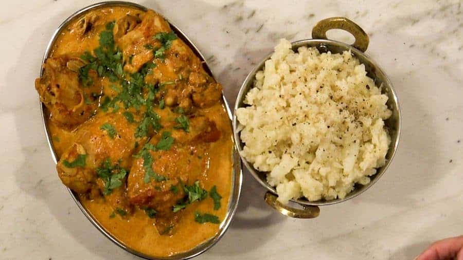 Overhead shot of finished butter chicken and steamed, mashed cauliflower.