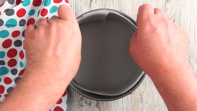 Overhead shot showing ring of parchment paper being placed along the sides of the springform pan