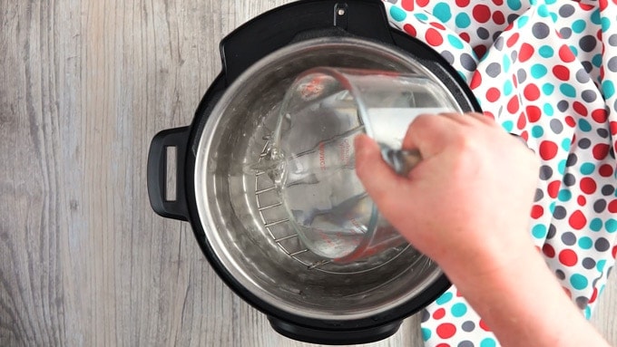 Overhead showing inside of instant pot with a trivet and water being poured