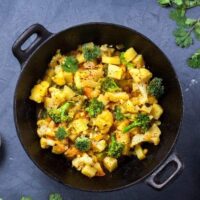 Indian Aloo Gobi dish with potato, cauliflower and spices on the textured grunge background