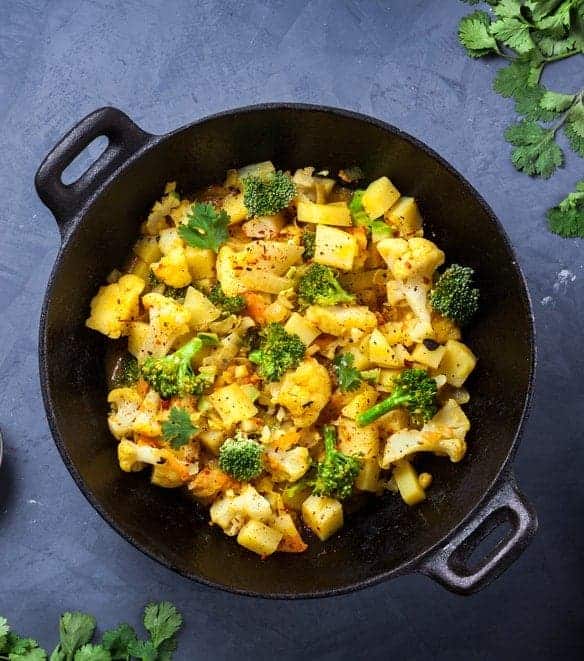 Indian Aloo Gobi dish with potato, cauliflower and spices on the textured grunge background