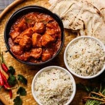Chicken tikka masala spicy curry meat food in cast iron pot with rice and naan bread close up