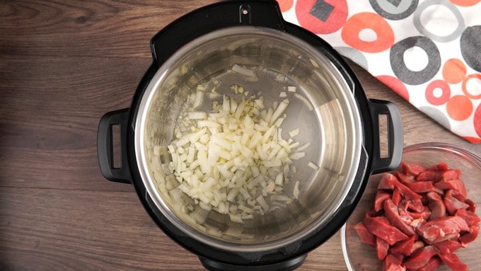 Overhead view of instant pot with oil, onions and garlic