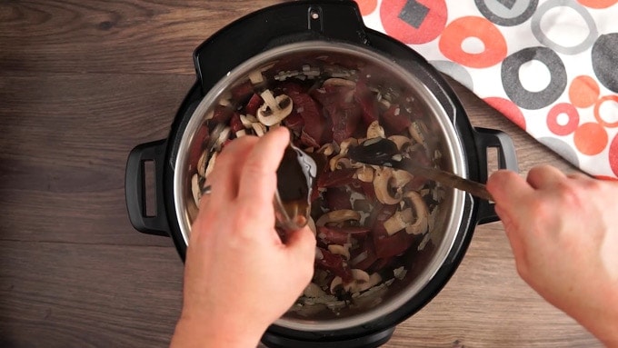 Overhead view of Adding in mushrooms, beef, Worcestershire sauce and water