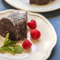 Keto Chocolate Cake on a white plate with raspberries and mint.