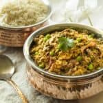 Instant Pot Indian Kheema recipe in small brass pot with rice at the back sideways view