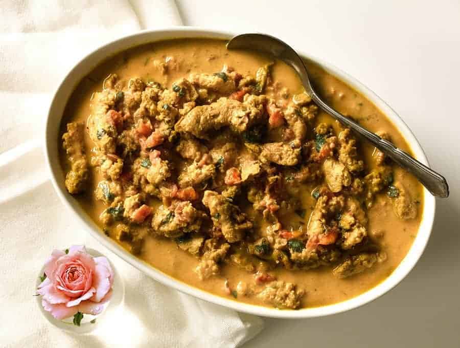 Vegetarian Butter Chicken with sauce in a white serving bowl with a spoon for serving. 