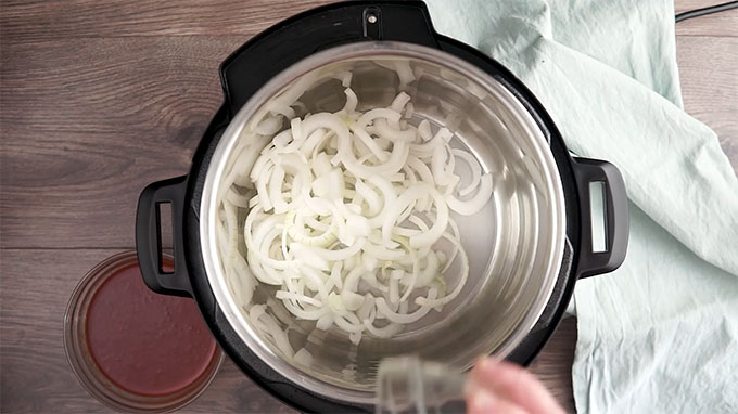 Overhead shot of a layer of onions in the bottom of the Instant Pot.