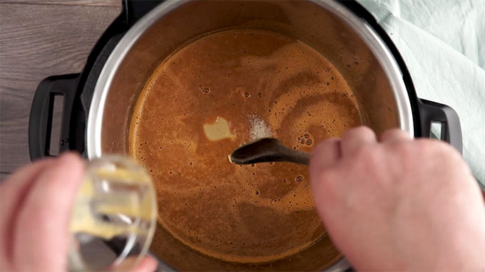 Overhead shot of adding mustard to the sauce in the Instant Pot.