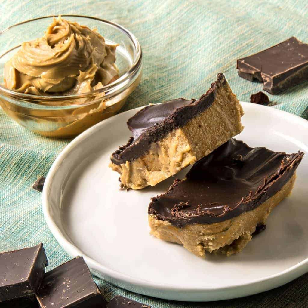 Keto dessert peanut butter bars on a plate with low sugar peanut butter in a bowl