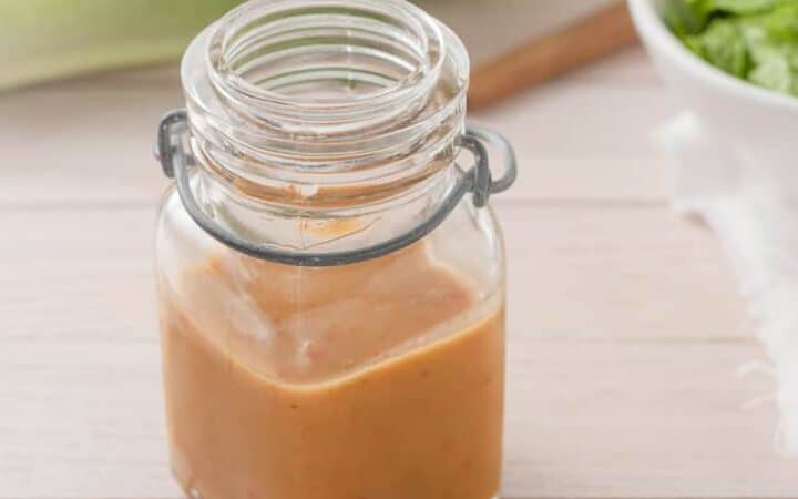 salad dressing in a glass container on light wooden background