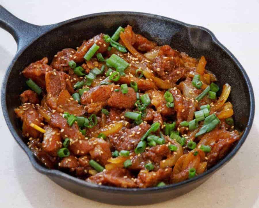 Overhead view of Dae Ji bulgogi in a cast iron pan. Savory Dae Ji Bulgogi Korean Spicy Pork cooks up flavorful and tender from your Instant Pot or Pressure cooker for a great low carb keto spicy pork dinner.
