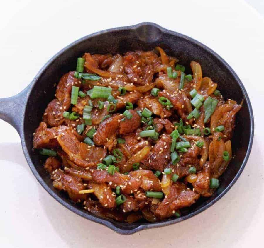 Overhead view of Dae Ji bulgogi in a cast iron pan. Savory Dae Ji Bulgogi Korean Spicy Pork cooks up flavorful and tender from your Instant Pot or Pressure cooker for a great low carb keto spicy pork dinner.