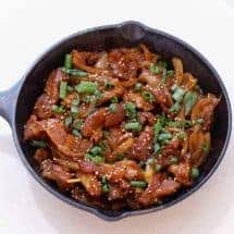 Overhead view of Dae Ji bulgogi in a cast iron pan. Savory Dae Ji Bulgogi Korean Spicy Pork cooks up flavorful and tender from your Instant Pot or Pressure cooker for a great low carb keto spicy pork dinner.