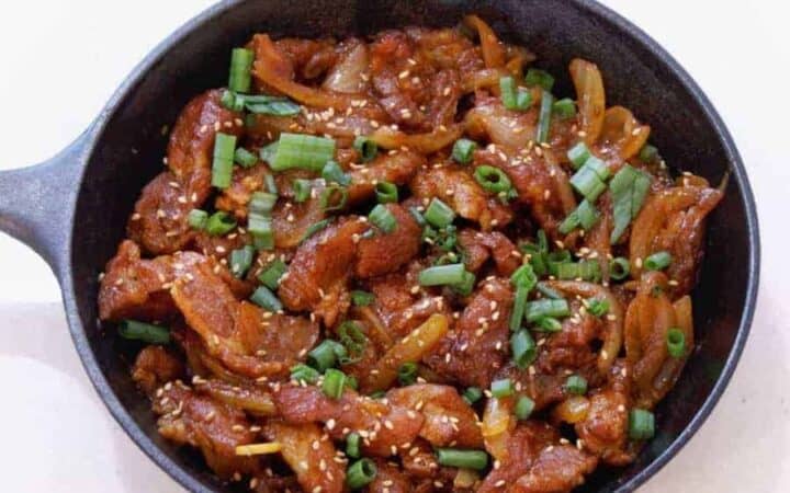 Overhead view of Dae Ji bulgogi in a cast iron pan. Savory Dae Ji Bulgogi Korean Spicy Pork cooks up flavorful and tender from your Instant Pot or Pressure cooker for a great low carb keto spicy pork dinner.