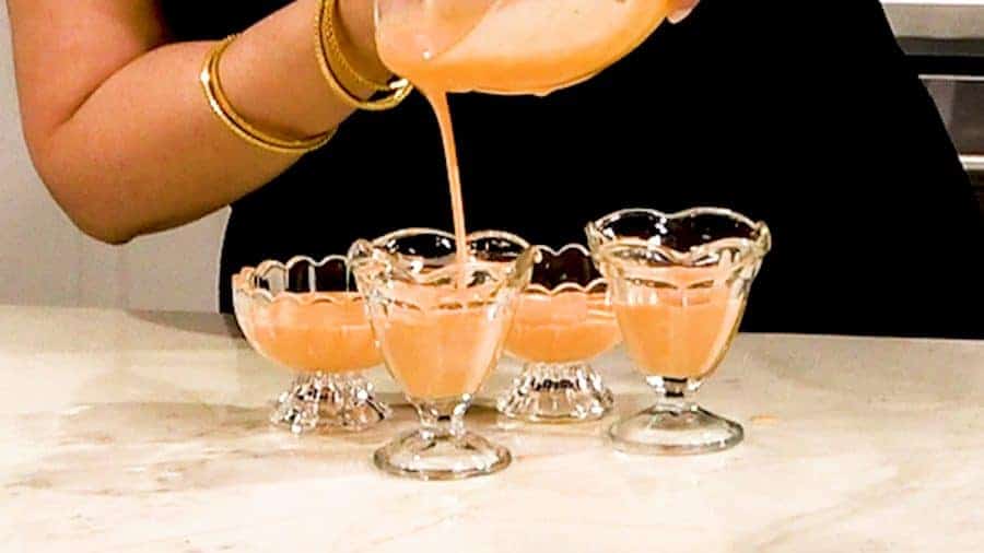 Side shot of pouring mixture into 4 ramekins.