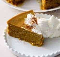 Sideways shot of a slice of crustless pumpkin pie. Perfect, crustless pumpkin pudding pie makes a lovely low carb pumpkin dessert in your Instant Pot or Pressure cooker. This is an easy dump and go dessert.