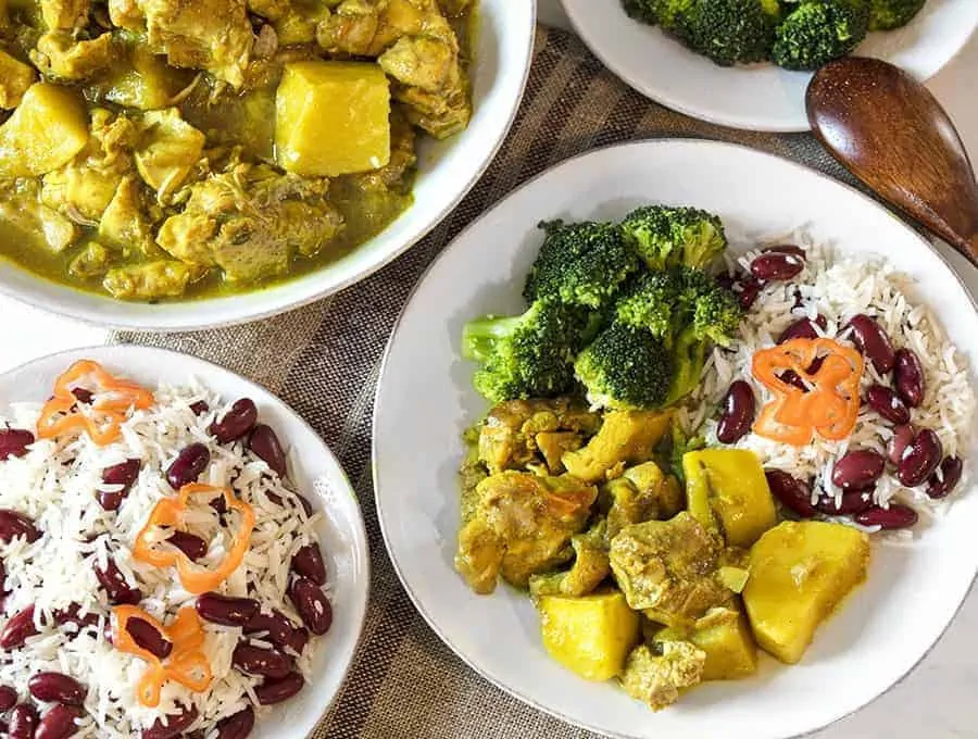 Jamaican Curry Chicken on a white plate served with rice and red beans 