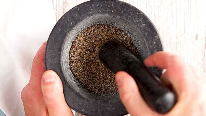 Overhead shot of pepper and salt being ground together in a mortar and pestle