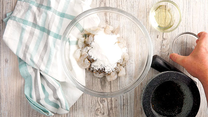 Rice flour being added to bowl of shrimp