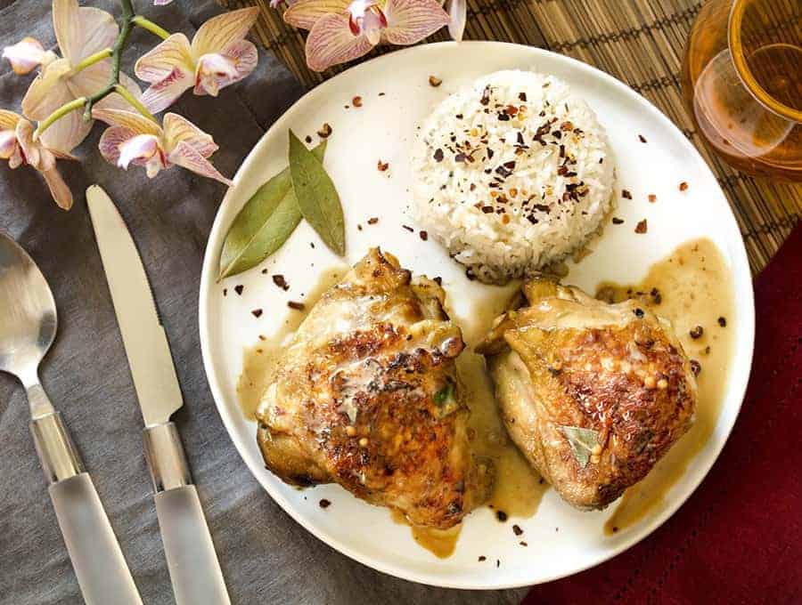 Instant Pot Chicken Adobo served with rice on a white plate with a knife and spoon.