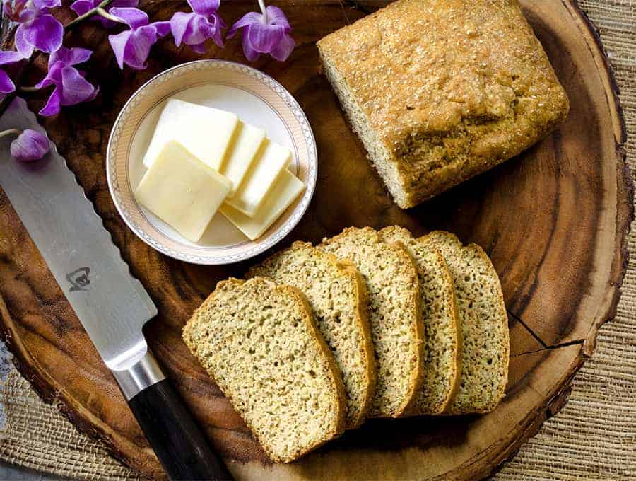 Keto Bread sliced on a wooden platter with dabs of butter and a knife