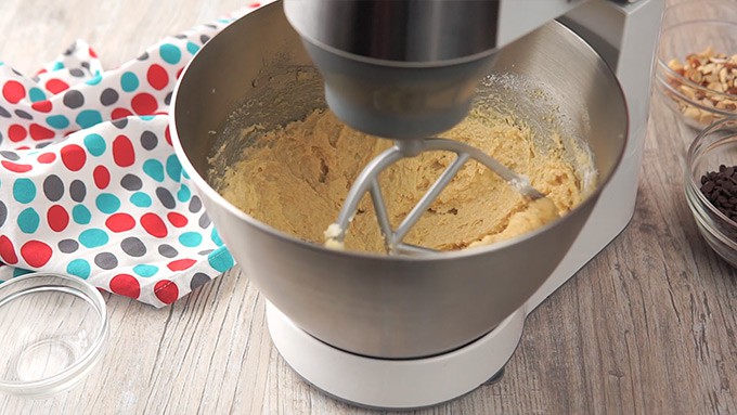Side shot of mixing the almond flour, baking powder, salt, and vanilla extract into the mixture.