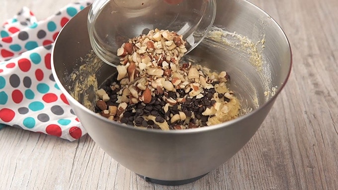 Side shot of adding the chocolate chips and nuts to the mixture.