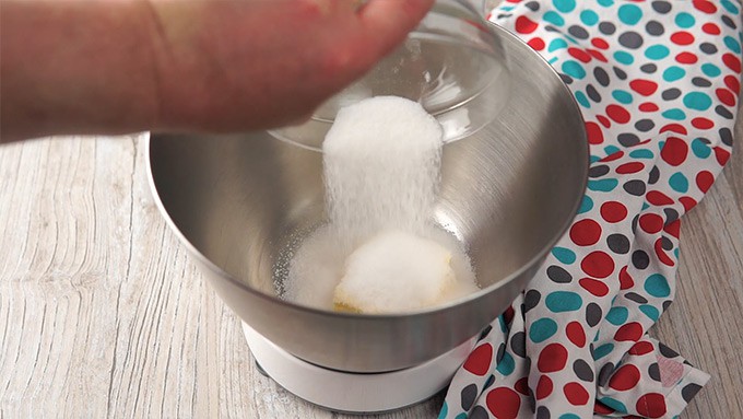 Side shot of addig sugar to the mixing bowl.