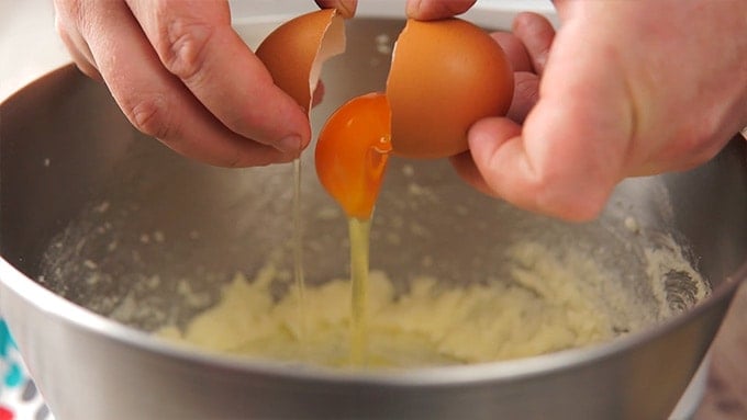 Side shot of adding the eggs to the mixing bowl.