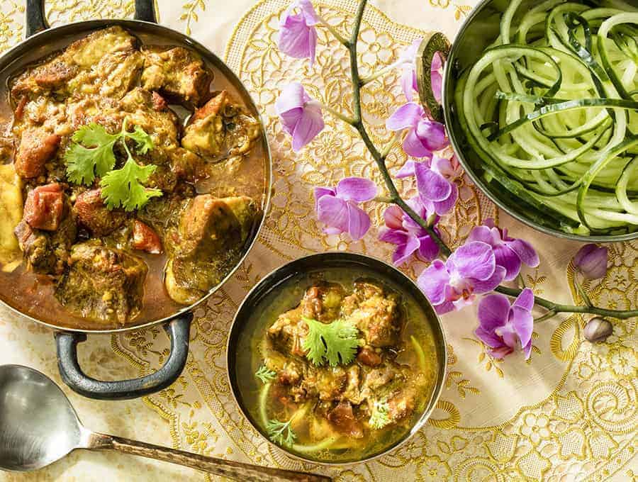 Indian Curry in a large sauce pot with a side dish of zoodles and a spoon