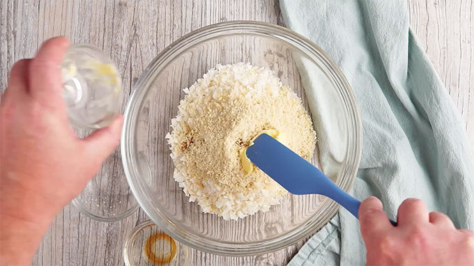 Almond flour, coconut, butter, and vanilla mixed together in a glass bowl.