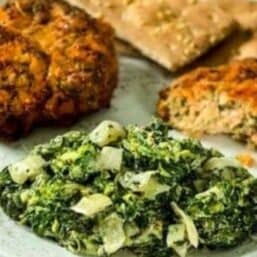 Keto creamed spinach on a white plate with salmon croquettes