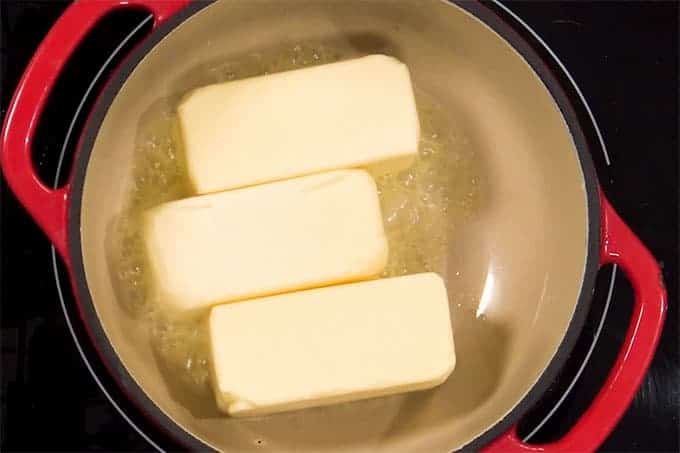 Overhead shot of 4 sticks of butter cooking in a pan.