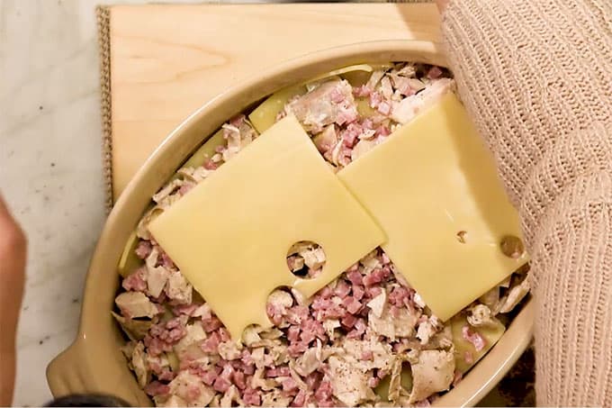 Overhead shot of the rest of the chicken and ham mixture in the pan with swiss cheese slices on top.