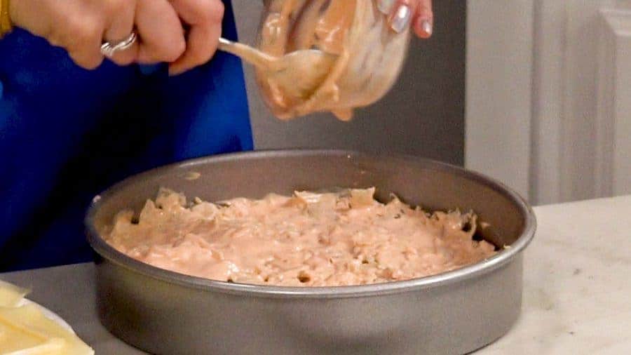 Pouring thousand island dressing into the casserole.