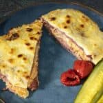 Baked reuben casserole cut into triangles with pickles