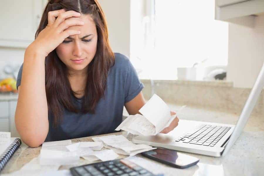 Brunette looking worried over bills in kitchen