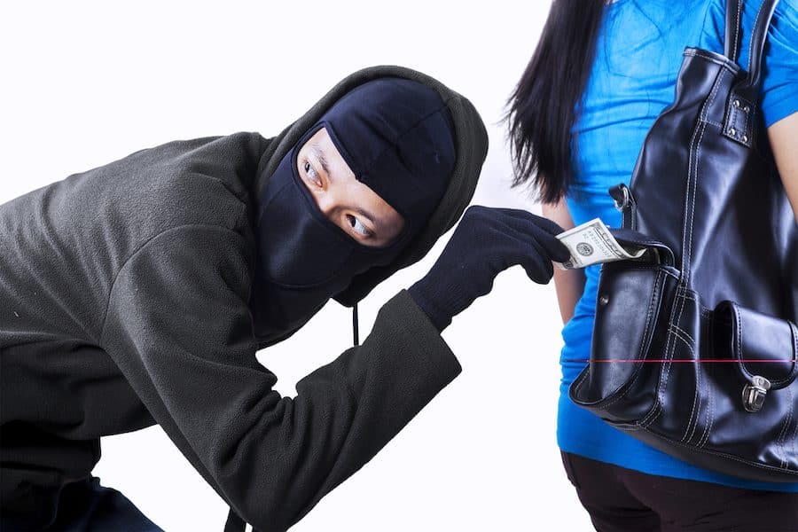 Thief stealing money from handbag of a woman