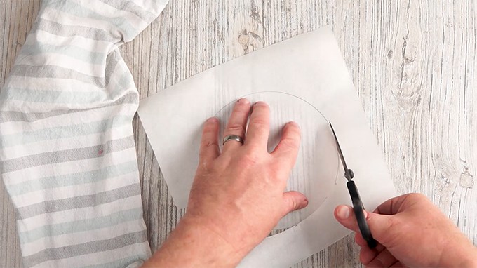Person using scissors to cut parchment paper in a circle.
