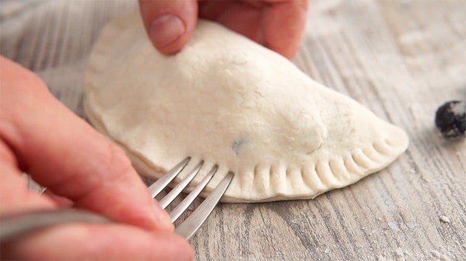 Crimping dough with a fork to seal fruit hand pies