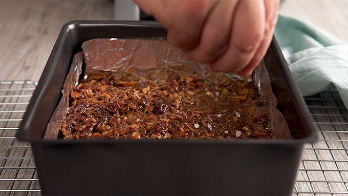 Sea Salt sprinkled on Maple Pecan Bars in a baking dish sitting on a cooling rack 