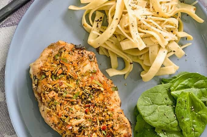 pork chop with pasta and salad on blue plate