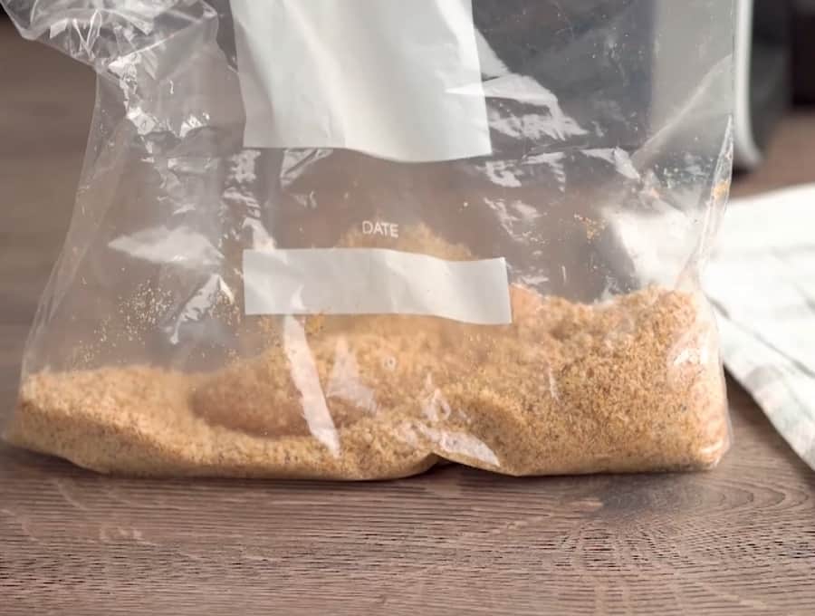 Side shot of a chicken tender being shaken in a ziptop bag with the breading ingredients.